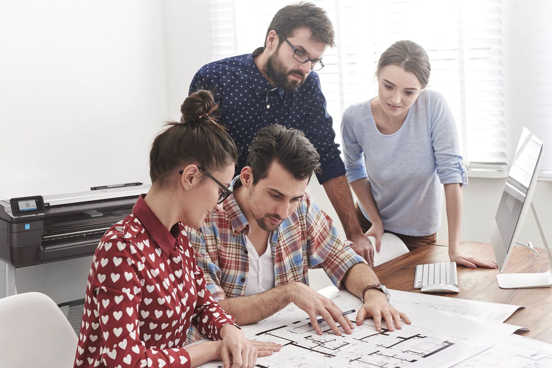 HP DesignJet plotter in an AEC office. Staff reviewing printed sheets. HP product photography.